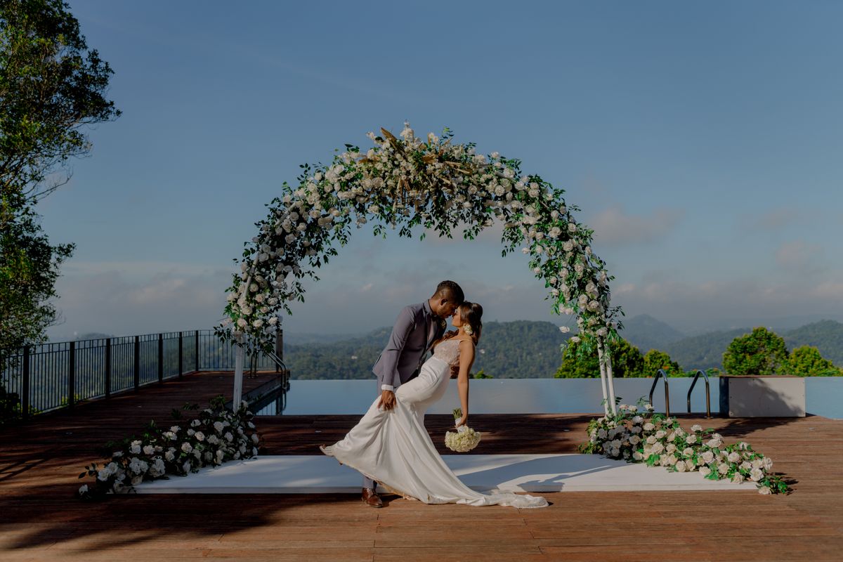 Bride and groom beneath a floral wedding arch