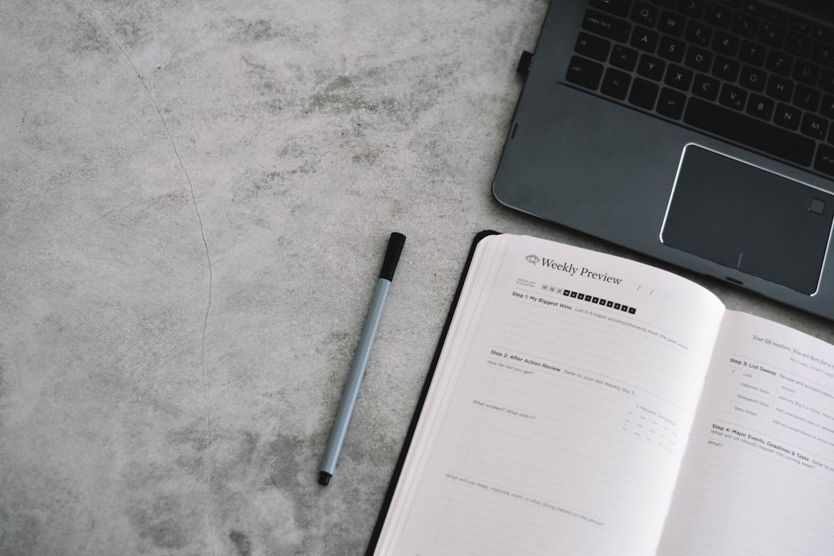 Digital planner creator working beside a laptop and planner