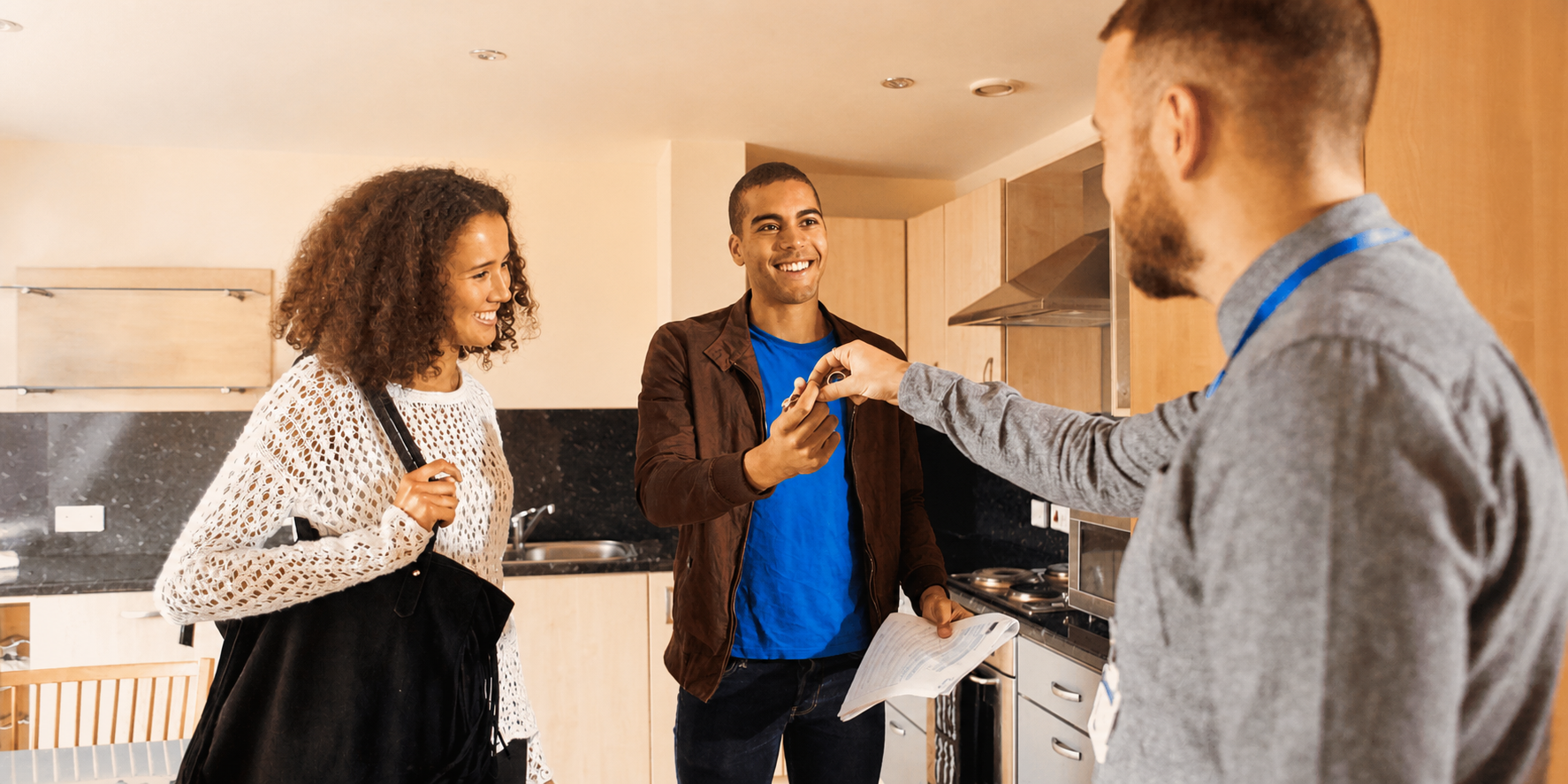 Real estate agent handing house keys to a smiling couple inside their new home