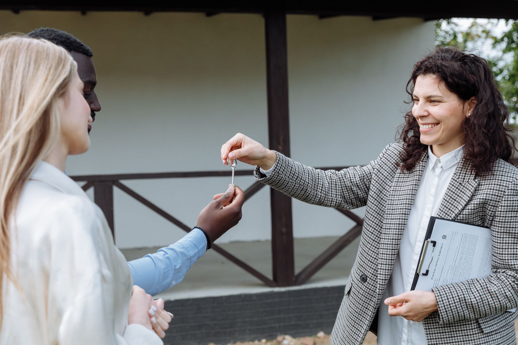 Real estate agent handing house keys to new homeowners outside their property